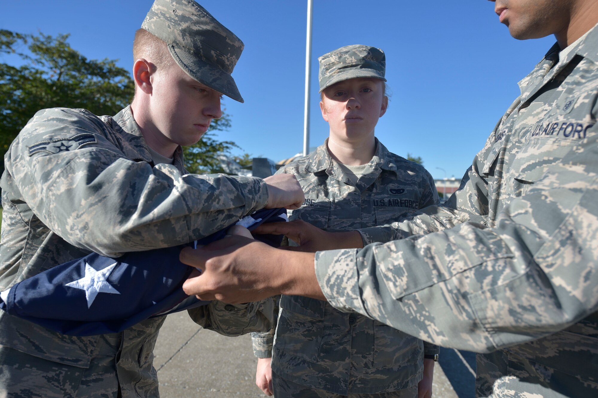 U.S. Air Force Airman 1st Class William Gage, left, Senior Airman Sarah Rose, center, and Senior Airman Francisco Valdepenas, right, all 35th Honor Guard guardsman practice retreat ceremony flag folding at Misawa Air Base, Japan, Sept. 17, 2018. The guardsman tour is a year-long additional duty that allows Airmen of all ranks to represent the Air Force through traditional ceremonial demonstrations. (U.S. Air Force photo by Tech. Sgt. Stephany Johnson)