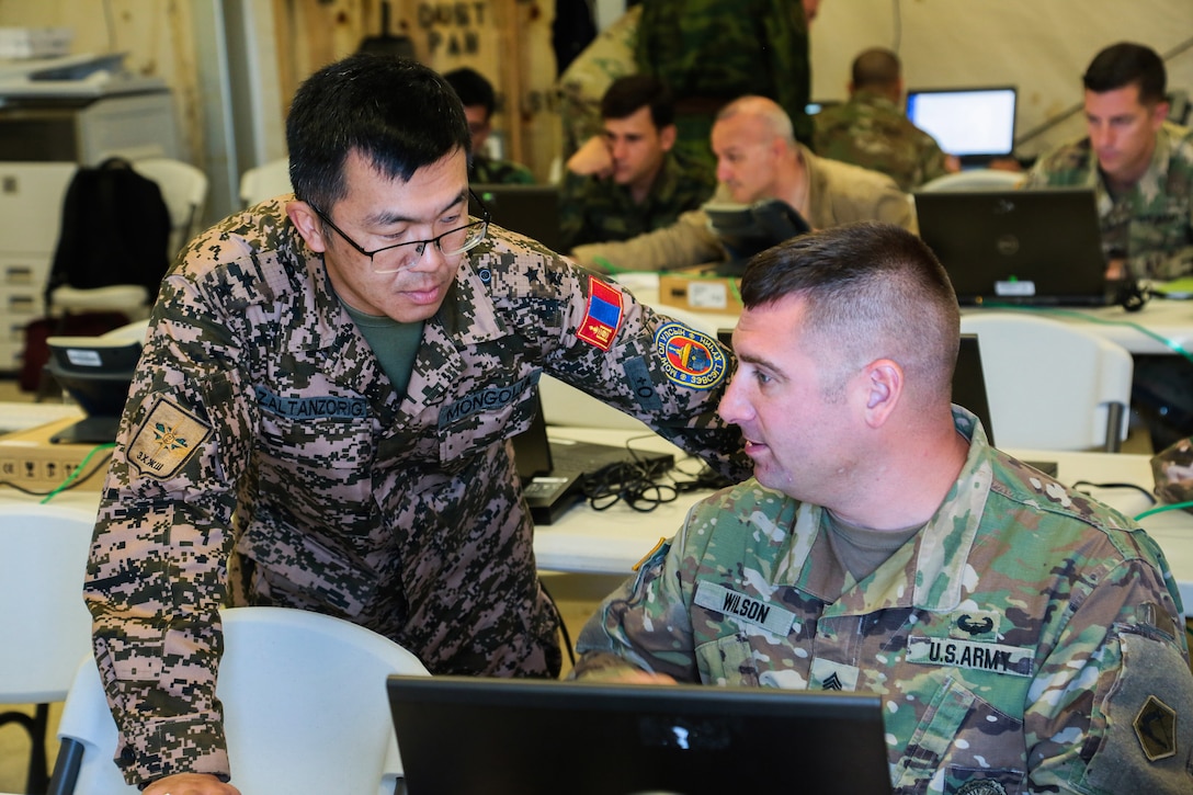 Mongolian Army Lt. Col. Z. Altanzorig (left) and Massachusetts Army National Guard Sgt. 1st Class Richard Wilson (right) evaluate a scenerio during command post exercise Regional Cooperation 18 at Camp Edwards on Joint Base Cape Cod, Massachusetts, Sept. 15, 2018. Regional Cooperation is an annual exercise conducted by multiple national partners focusing on stability operations, border security and control, counter terrorism, counter narcotics, and counter proliferation. (U.S. Central Command Public Affairs photo by Tom Gagnier)