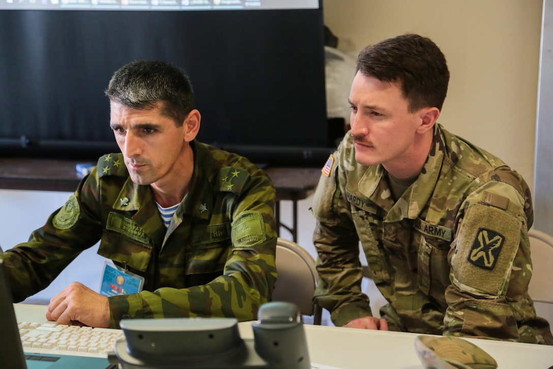 Utah Army National Guard Spec. Chanson Hardy (right) and a Tajik National Army officer evaluate a scenario during command post exercise Regional Cooperation 18 (RC18) at Camp Edwards on Joint Base Cape Cod, Massachusetts, Sept. 15, 2018. Regional Cooperation is an annual exercise conducted by multiple national partners that strengthens military-to-military relationships between U.S. forces and nations in Central and South Asia.  The exercise enhances regional security and stability by exercising a response to current regional security concerns. (U.S. Central Command Public Affairs photo by Tom Gagnier)