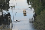 A U.S. Army high clearance vehicle makes its way to a stranded pick up truck on a flooded roadway near Nichols, South Carolina, Sept. 18, 2018.