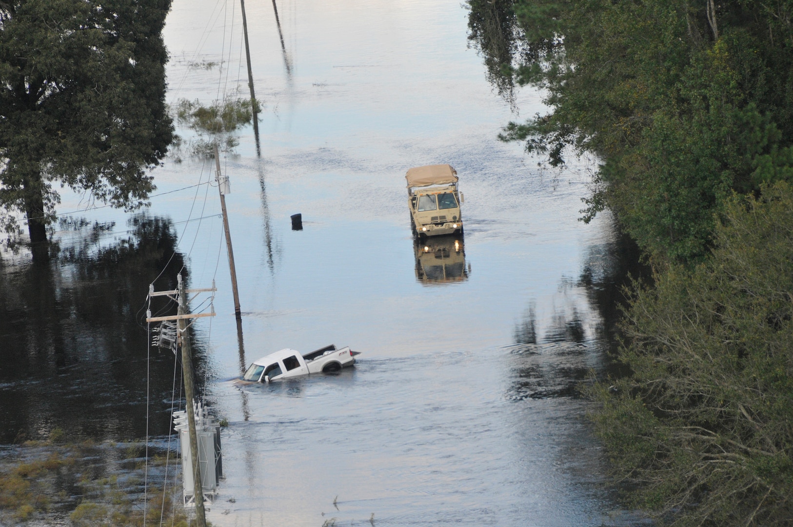 A U.S. Army high clearance vehicle makes its way to a stranded pick up truck on a flooded roadway near Nichols, South Carolina, Sept. 18, 2018.