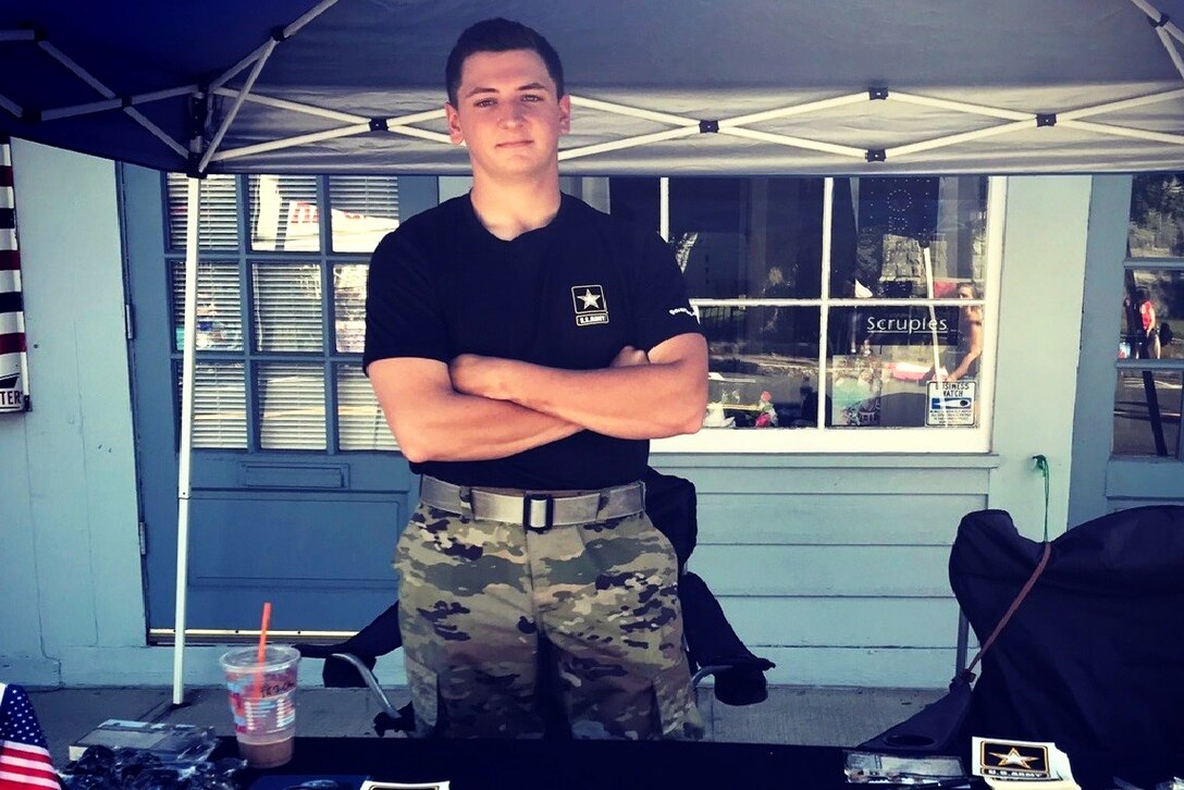 An Army recruiter stands behind a table.