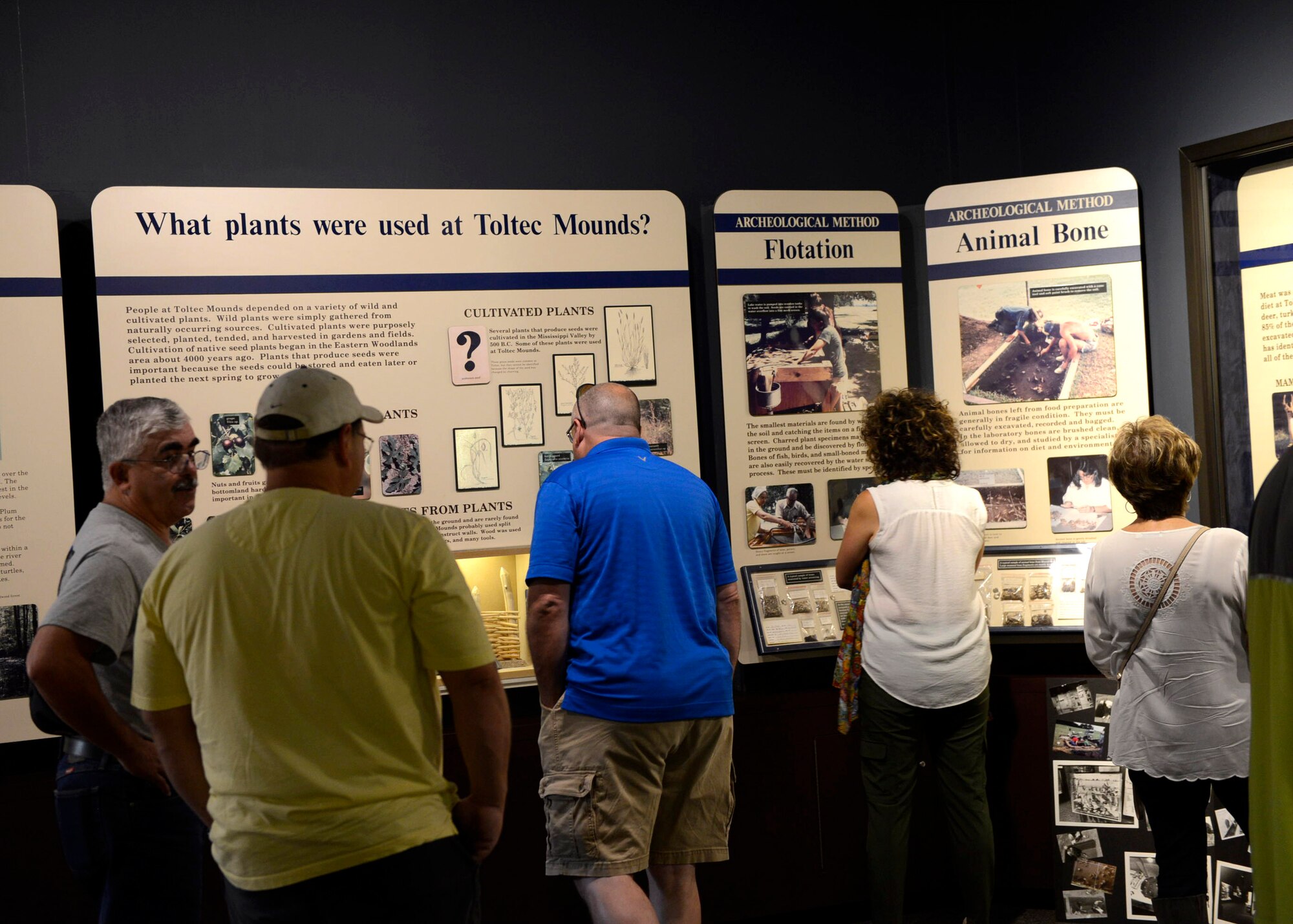 A group of white females and males look at displays at a museum.