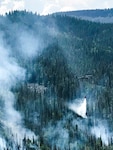 A UH-60 Black Hawk helicopter, equipped with an aerial water bucket, from the Chief Warrant Officer 5 David R. Carter Army Aviation Support Facility based at Buckley Air Force Base, Aurora, Colorado, drops water on the Cache Creek Fire, in Garfield County, Colorado, to support fire suppression efforts Aug. 17, 2018. The team, with two UH-60s, arrived and began operations Aug. 14. (Courtesy Photo by Lt. James Woods, Mountain View Fire Rescue)