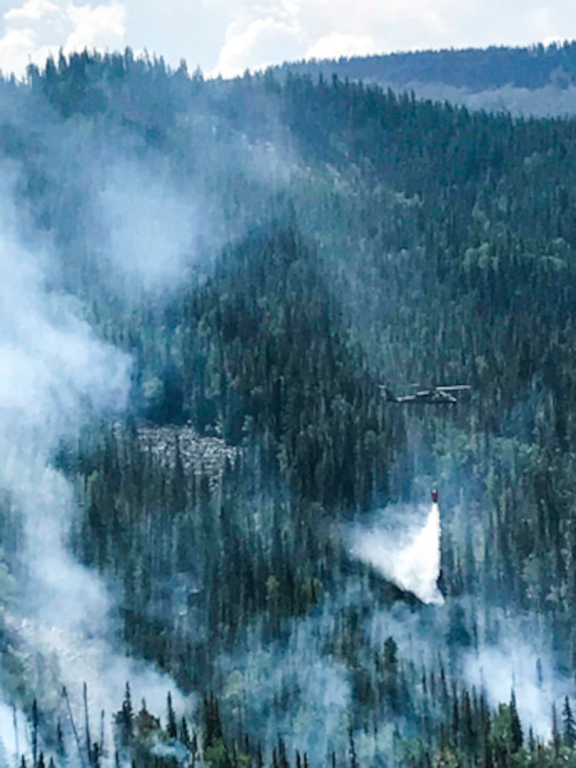 A UH-60 Black Hawk helicopter, equipped with an aerial water bucket, from the Chief Warrant Officer 5 David R. Carter Army Aviation Support Facility based at Buckley Air Force Base, Aurora, Colorado, drops water on the Cache Creek Fire, in Garfield County, Colorado, to support fire suppression efforts Aug. 17, 2018. The team, with two UH-60s, arrived and began operations Aug. 14. (Courtesy Photo by Lt. James Woods, Mountain View Fire Rescue)
