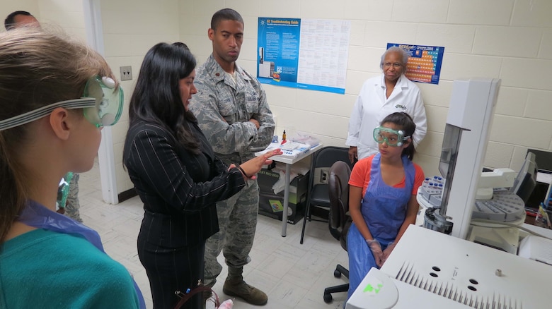 Diana Velosa (center, in black) a chemist with the Air Force Technical Applications Center, provides mentorship to Dayana Paz (seated) during the June 2015 STEMversity program on the campus of Central State Hospital in Georgia.  Velosa and fellow AFTAC member Maj. Allen Cohen (pictured), attended the summer program that focuses on STEM and gives underrepresented middle and high school youth an opportunity to conduct experiments and use precision instruments in real-life laboratories.  (U.S. Air Force photo by Rose Day)