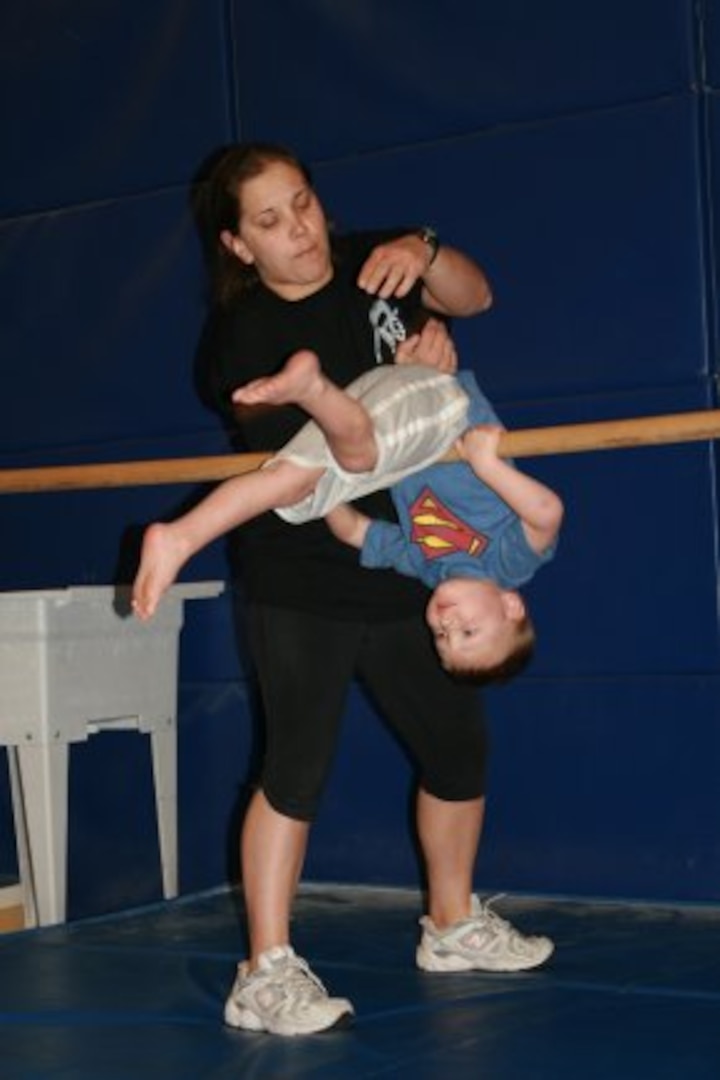 ​Gymnastics Instructor Jillian Frank helps 3-year-old Colton Taylor flip over a bar during a gymnastics class April 2, 2012 at Fort Carson, Colo. Taylor battled a rare form of cancer for more than two years, but now participates in the activities most children his age enjoy. (Photo credit: For Carson Public Affairs)