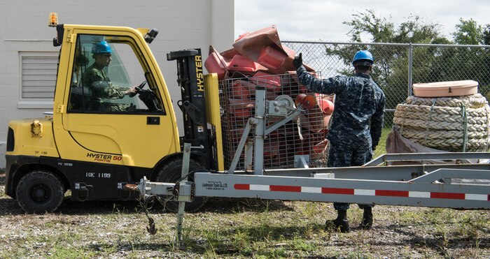 U.S. Navy Machinist Mate 2nd Class Vincent Brown, right, Harbor Patrol Unit, directs U.S. Navy Machinist Mate 2nd Class Andrew Kessler, left, Harbor Patrol Unit, where to place the material on the forklift at the Naval Weapons Station’s port operations building at Joint Base Charleston, S.C. Sept. 17, 2018. Team members are resuming normal operations after Hurricane Florence by moving equipment and material back into service from sheltered storage.