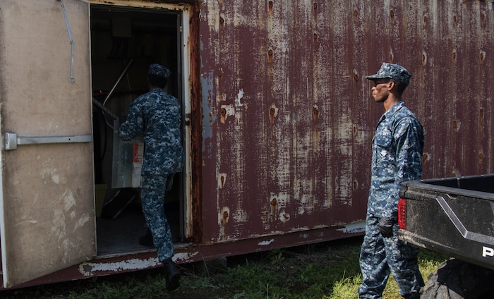 U.S. Navy Yeoman 2nd Class Anthony O’Neal, Harbor Patrol Unit and U.S. Navy Seaman Darien Kelly, Harbor Patrol Unit move material into a storage box at the Naval Weapons Station’s port operations building Sept. 17, 2018 Joint Base Charleston, S.C. Team members are resuming normal operations after Hurricane Florence by moving equipment and material back into service from sheltered storage.