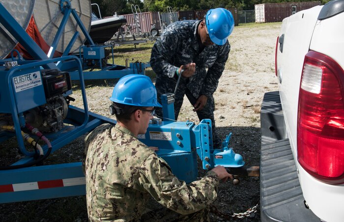 U.S. Navy Machinist Mate 2nd Class Vincent Brown, back, Harbor Patrol Unit and U.S. Navy Machinist Mate 2nd Class Andrew Kessler, front, Harbor Patrol Unit, hook a trailer to a truck, at the Naval Weapons Station’s port operations building Sept. 17, 2018 at Joint Base Charleston, S.C. Team members are resuming normal operations after Hurricane Florence by moving equipment and material back into service from sheltered storage.