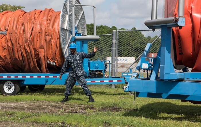 U.S. Navy Machinist Mate 2nd Class Vincent Brown, Harbor Patrol Unit at Joint Base Charleston, S.C., directs a truck Sept. 17, 2018, as it moves a boat boom at the Naval Weapons Station’s port operations building.