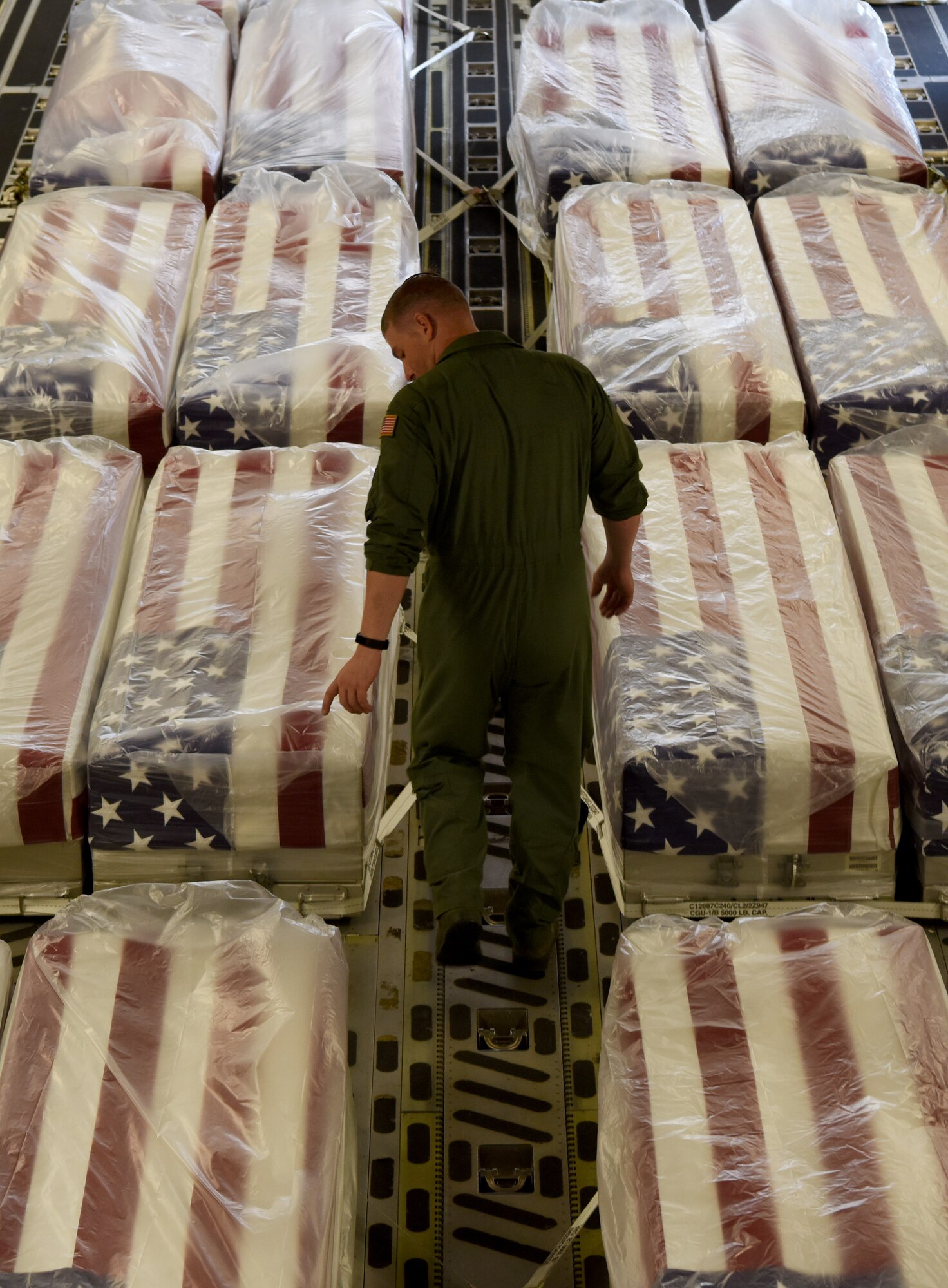 U.S. Air Force Tech. Sgt. Joe Chamberlain, 437th Aircraft Maintenance Squadron flying crew chief, ensures the transfer cases are secure onto a C-17 Globemaster III for the repatriation of 26 WWII human remains Sept. 13, 2018, at Ramstein Air Base, Germany. Aircrew from Joint Base Charleston, S.C. was tasked to deliver the remains due to its rapid mobility capabilities.