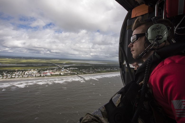 A pararescueman assigned to the 334th Air Expeditionary Group scans the coastline, Sept. 16, 2018, in the skies over South Carolina. The 334th AEG is an expeditionary search and rescue unit, which is pre-positioned to provide relief in the wake of tropical storm Florence. Comprised of 23d Wing and 920th Rescue Wing personnel and assets, the 334th AEG is ready to perform surface, fixed wing and rotary SAR operations when needed.