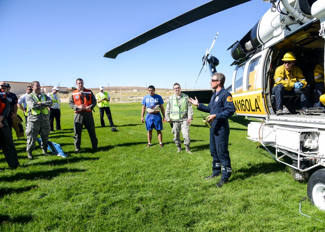 Crew Chief Mike Dubron, a firefighter and paramedic with the Los Angeles County Fire Department, briefs first responders on his helicopter and crew’s capabilities immediately following an active shooter scenario exercise at Desert Junior-Senior High School at Edwards Air Force Base, California, Sept. 18, 2018. The helicopter crew shared information such as required medevac landing zone sizes with the Edwards emergency first responders. (U.S. Air Force photo by Giancarlo Casem)