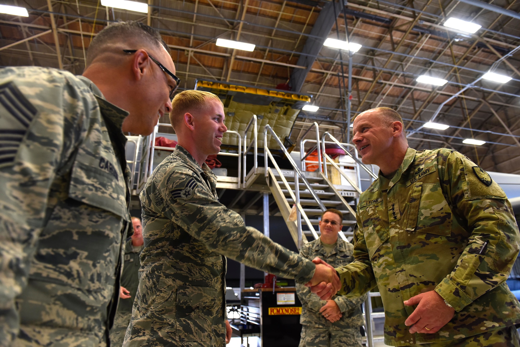 U.S. Army Gen. Stephen Lyons, U.S. Transportation Command commander, coins Senior Airman Nicholas Thurman, 92nd Aircraft Maintenance Squadron crew chief, at Fairchild Air Force Base, Washington, Sept. 19, 2018.