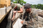U.S. Marine and Guatemalen engineer lay blocks at a construction site.