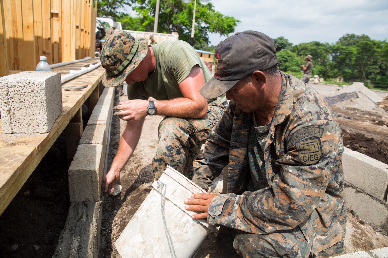 U.S. Marine and Guatemalen engineer lay blocks at a construction site.