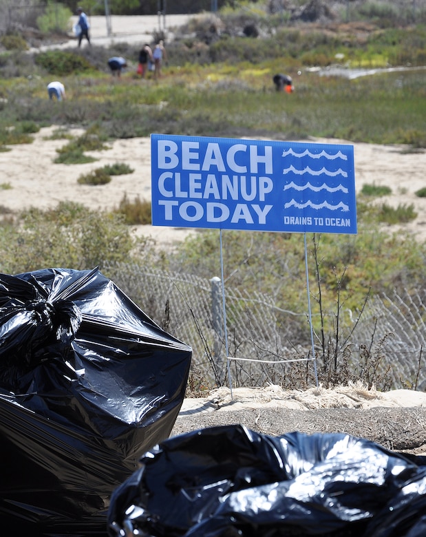 A “beach cleanup sign” sits in the foreground as volunteers pick up trash from the Santa Ana River Marsh Sept. 15 in Newport Beach, California. The event was part of California Coastal Cleanup Day.