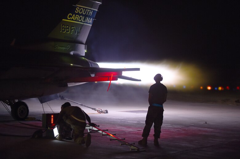An  F-16 Fighting Falcon performs and afterburner run on the flightline at night