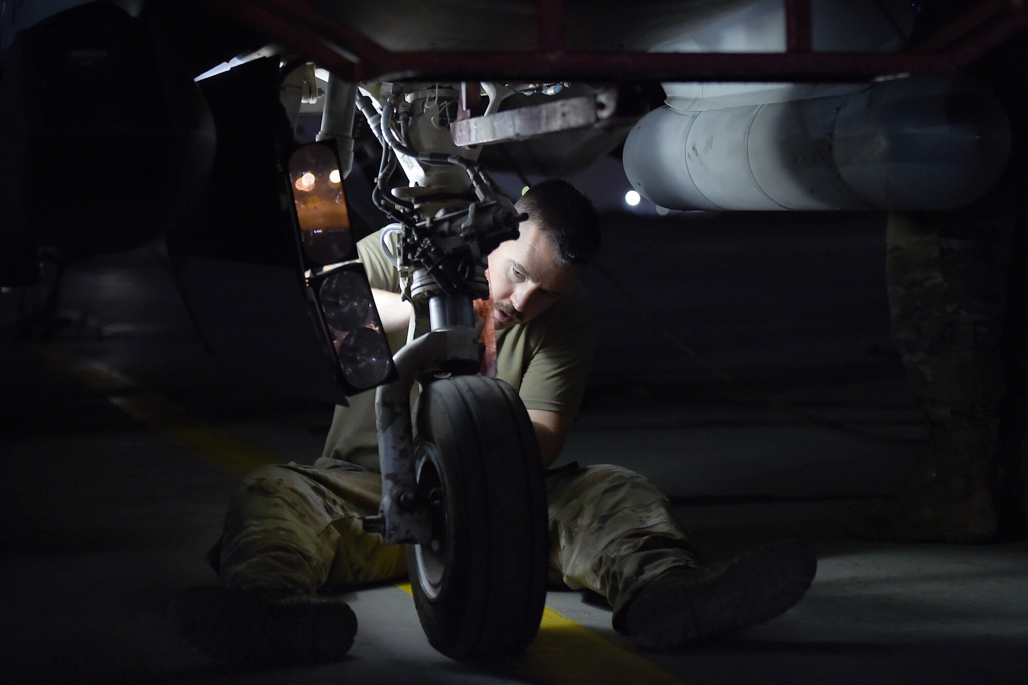 An Airmen works on the flightline at night