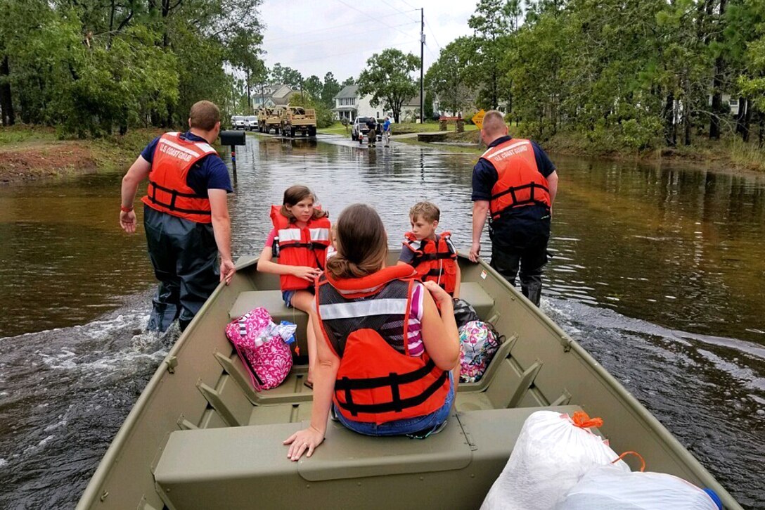Coast Guard members rescue civilians after a dam breach caused flooding and trapped residents in their homes.