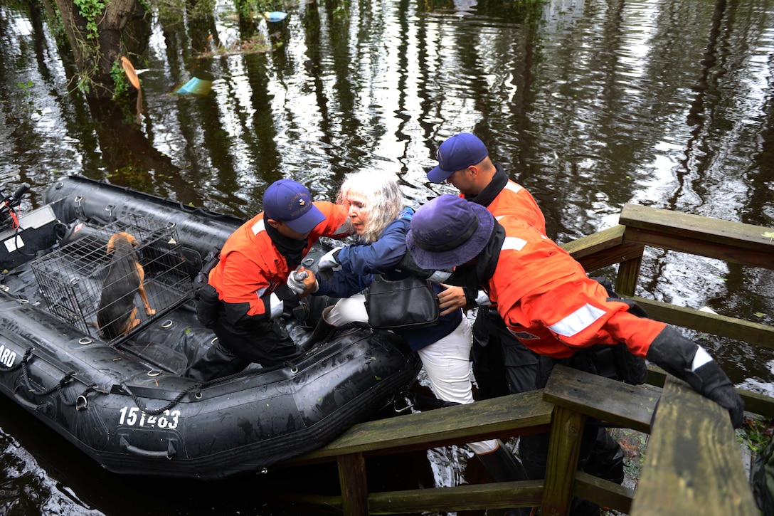 Coast Guard members rescue an elderly woman and her husband along with their pets after their home was flooded.