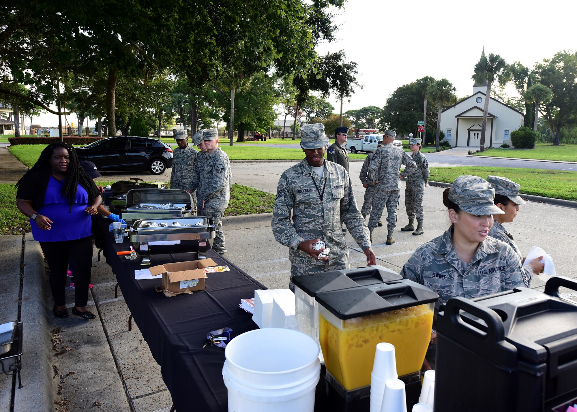Tashara Mckinzycole, 325th Force Support Squadron marketing director, left, watches as 325th Fighter Wing Airmen proceed through a food line at Flag Park on Tyndall Air Force Base, Fla., Sept. 18, 2018. The 325th FSS treated 325th FW Airmen to a free breakfast to celebrate the 71st birthday of the Air Force. (U.S. Air Force photo by Senior Airman Isaiah J. Soliz)