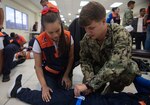 A U.S. Navy Sailor demonstrates proper tourniquet techniques with a Honduran emergency response medical professional.