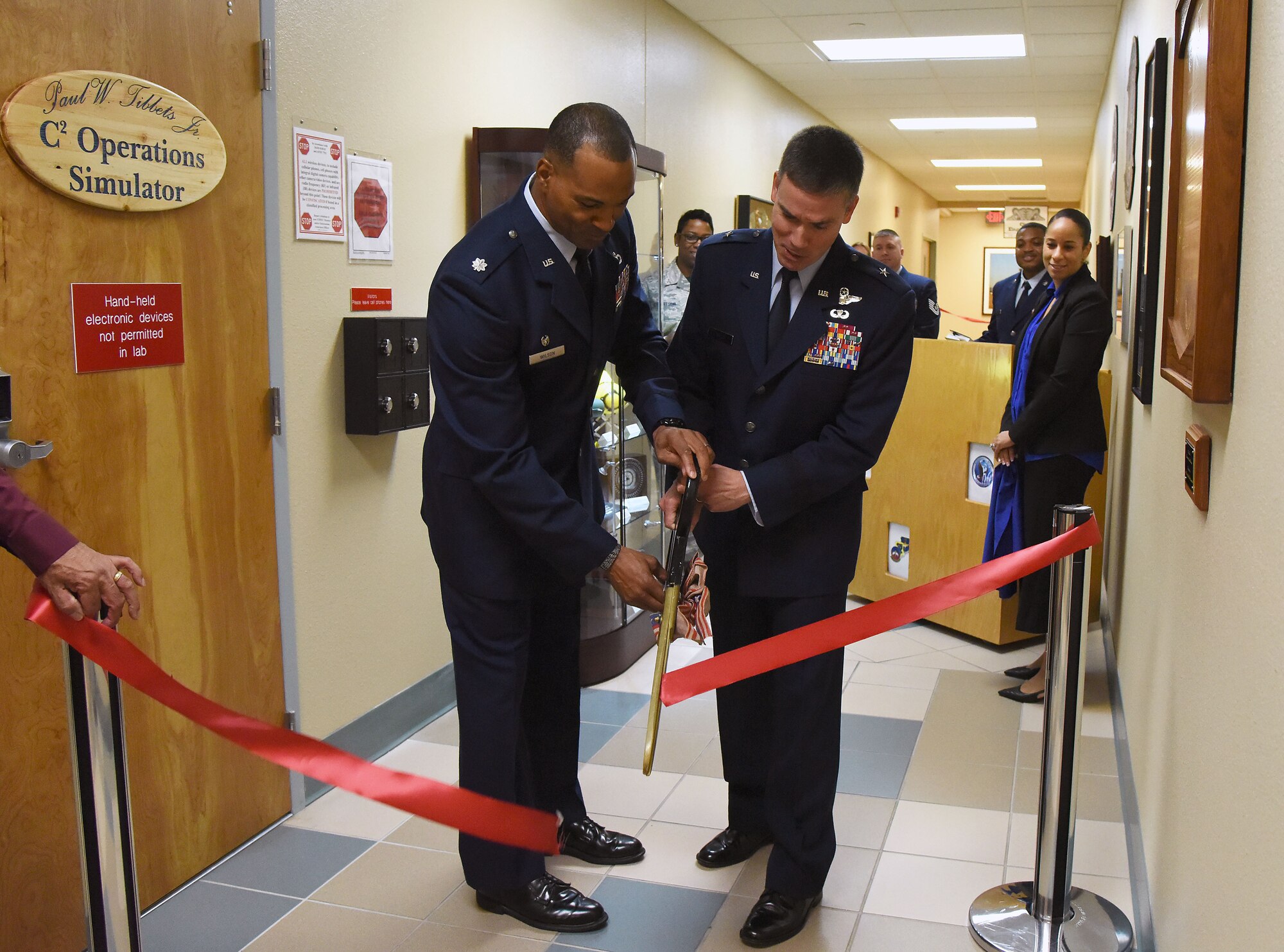 U.S. Air Force Lt. Col. Billy Wilson, 334th Training Squadron commander, and Brig. Gen. Paul W. Tibbets IV, Air Force Global Strike Command deputy commander, Barksdale Air Force Base, Louisiana, participates in a ribbon cutting ceremony during a room dedication ceremony at Cody Hall on Keesler Air Force Base, Mississippi, Sept. 14, 2018. The dedication honored Tibbets' grandfather, retired Brig. Gen. Paul W. Tibbets Jr., by dedicating the 334th Training Squadron Command and Control simulator in his name. Tibbets Jr., piloted the Enola Gay, which dropped the world's first atomic bomb. (U.S. Air Force photo by Kemberly Groue)