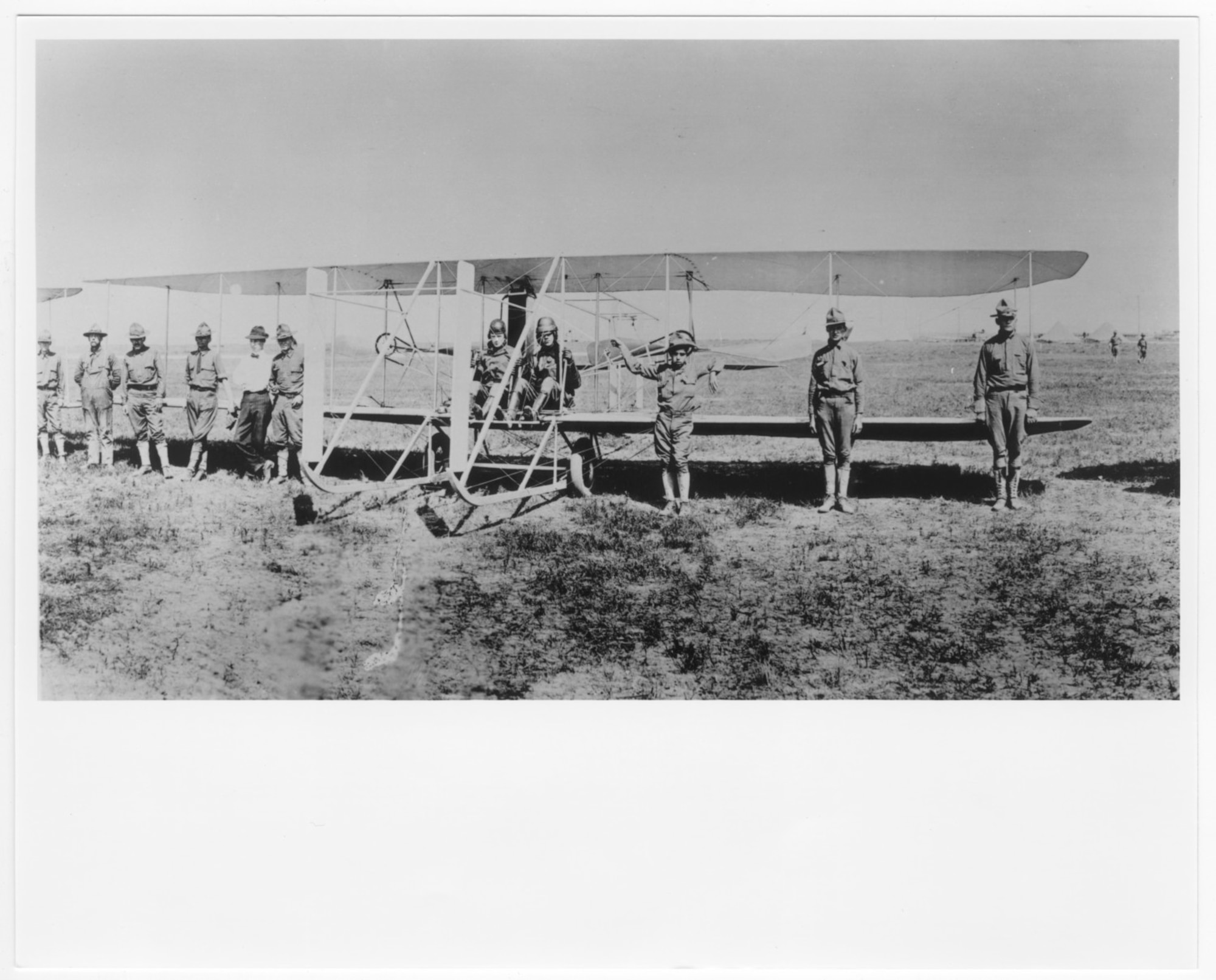 In the year of the 1st Aero Squadron's formation, Lt. Thomas D. Milling, instructor, and Lt. Fred Seydel, student, are at the controls of a Wright C., SC-16 Trainer on airfield in Texas City, Texas, May 1913. In front of the plane, 8 other soldiers in uniform and a civilian in white shirt and bow tie stand posed facing the camera. (U.S. Air Force Museum Courtesy photo)