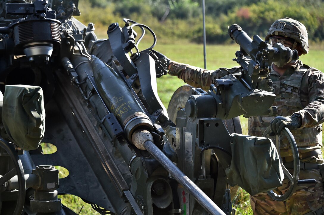 A soldier calibrates and inputs the firing coordinates for an M777 howitzer during a live-fire exercise.