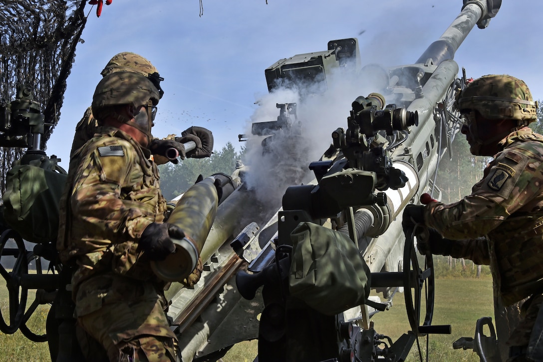 Soldiers load a 155 mm round into an M777 howitzer during a live-fire exercise.