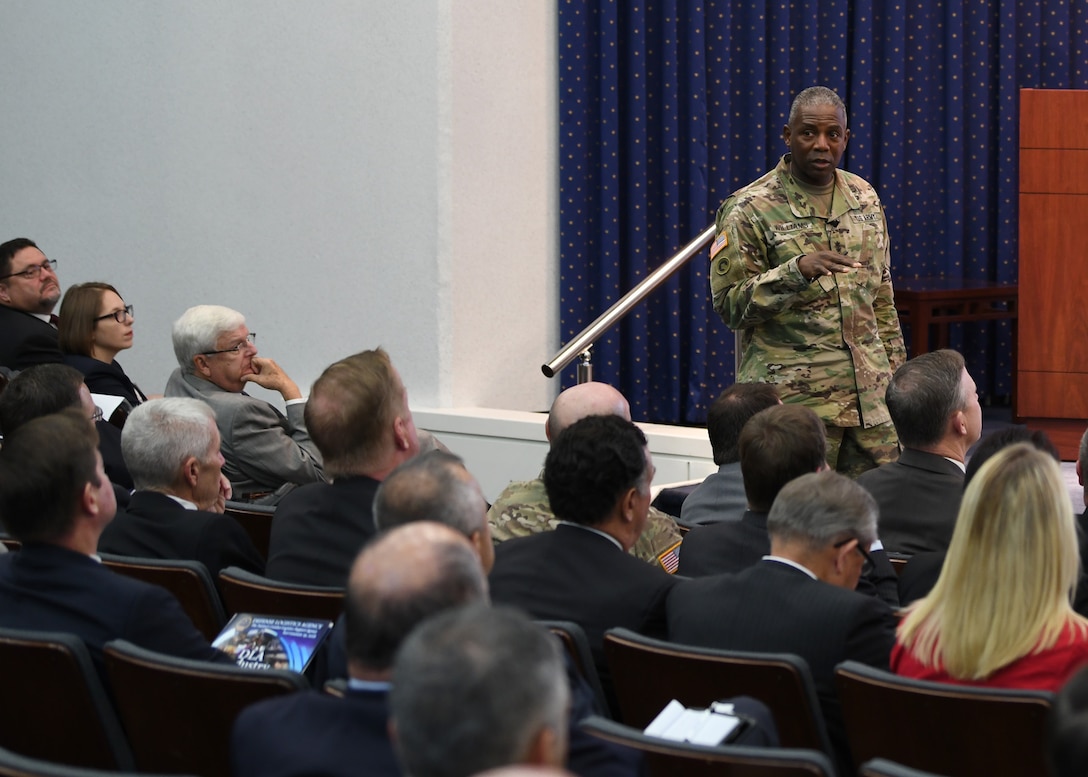 General in fatigues talking to seated audience