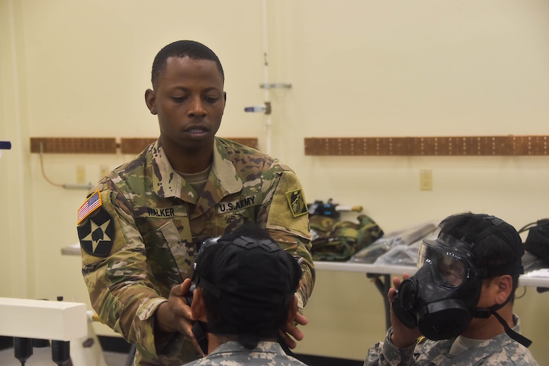 Capt. Courtney Walker, U.S. Army Corps of Engineers, Far East District operations officer, assists Emergency Essential Civilian (EEC) personnel with fitting their gas masks during the district's EEC training held at the Vehicle Maintenance Facility, Aug. 22.