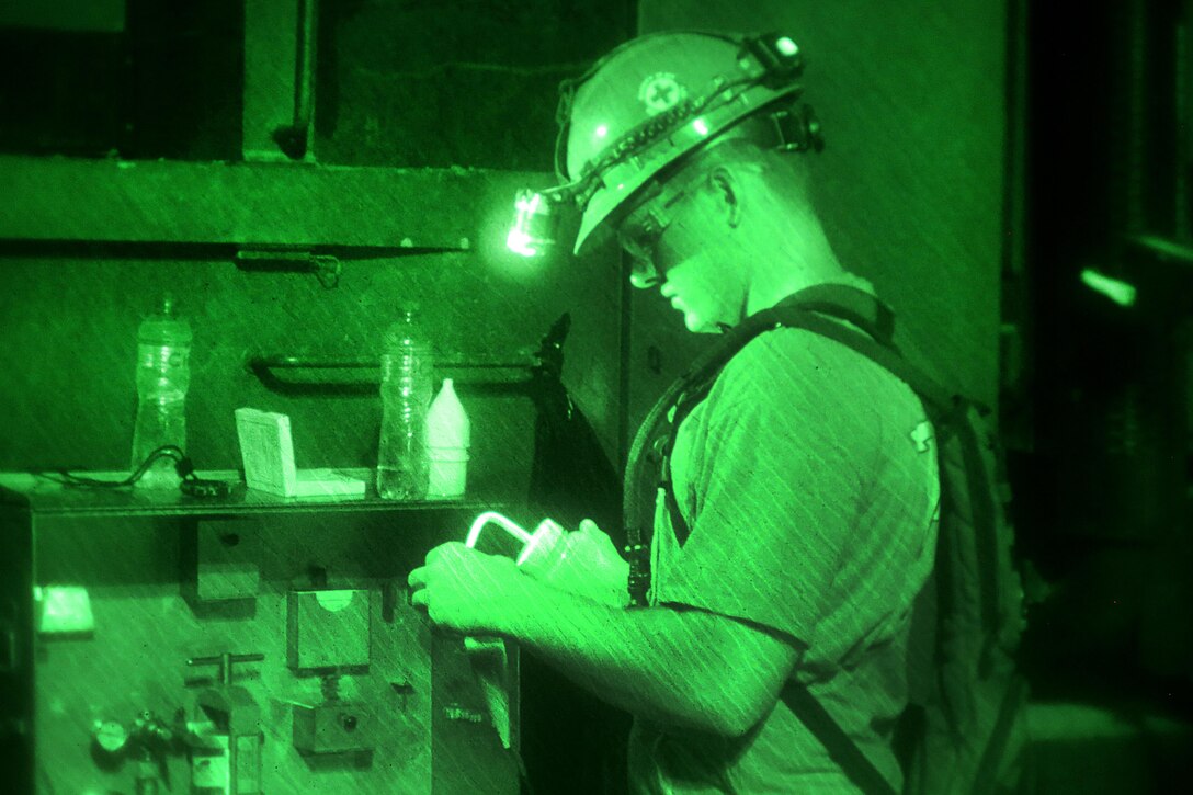 A sailor conducts a sand content test while conducting a water well exploration operation.
