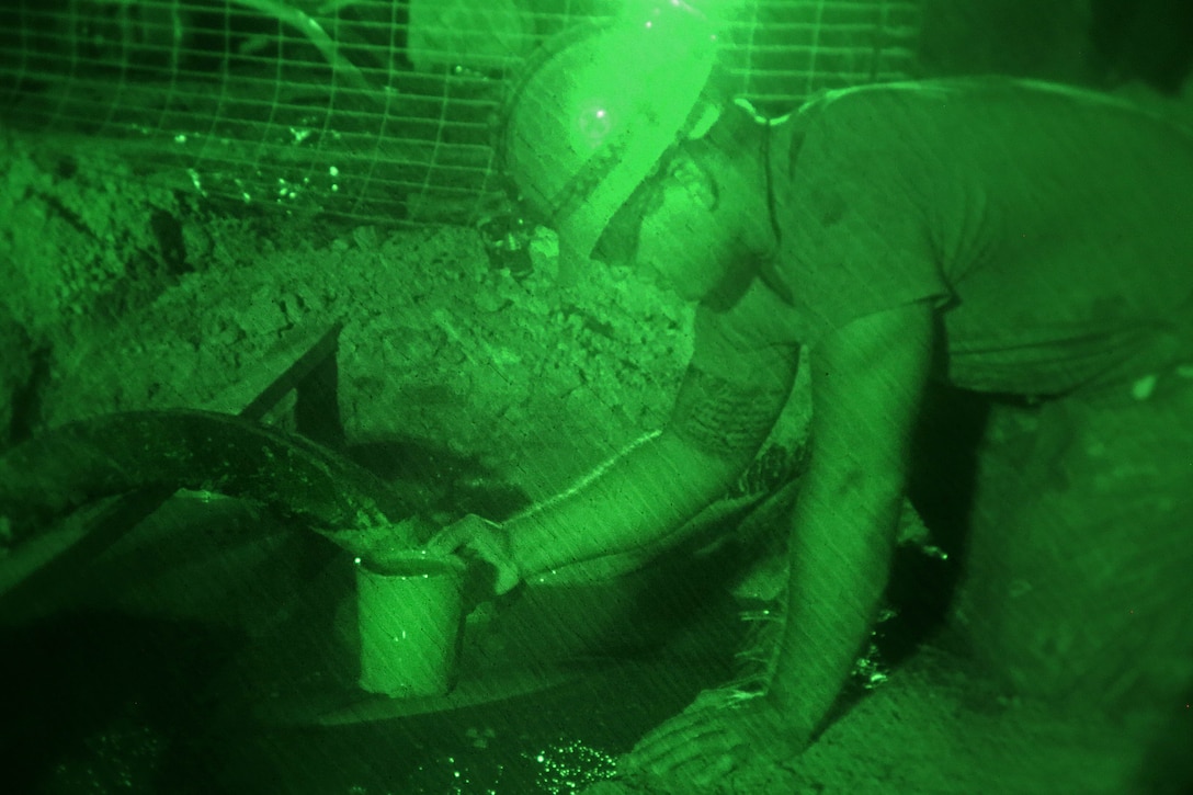 A sailor collects mud for a test during a water well exploration operation.