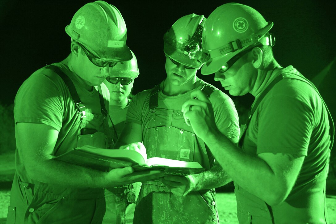 Sailors review a drilling manual during a water well exploration operation.