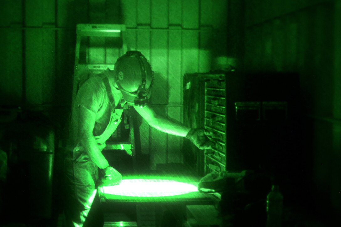 A sailor searches for a tool while conducting a water well exploration operation.