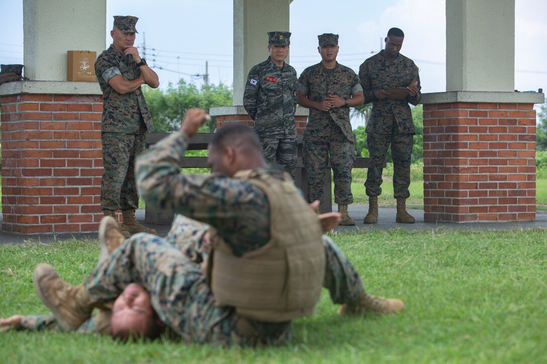 Marines with 3rd Maintenance Battalion, 3rd Marine Logistics Group, demonstrate Marine Corps Martial Arts Program techniques for Sgt. Maj. Jong Ik Jun, sergeant major of the Republic of Korea Marine Corps, Sept. 20, 2018 at Camp Kinser, Okinawa, Japan. Jun visited Camp Kinser to observe the Non-Commissioned Officer driving-force of small unit leadership within the U.S. Marine Corps. Republic of Korea and United States Marine Corps forces are committed to the ironclad ROK-U.S. alliance and work together to further develop their partnership and combined capabilities. (U.S. Marine Corps photo by Lance Cpl. Armando Elizalde)
