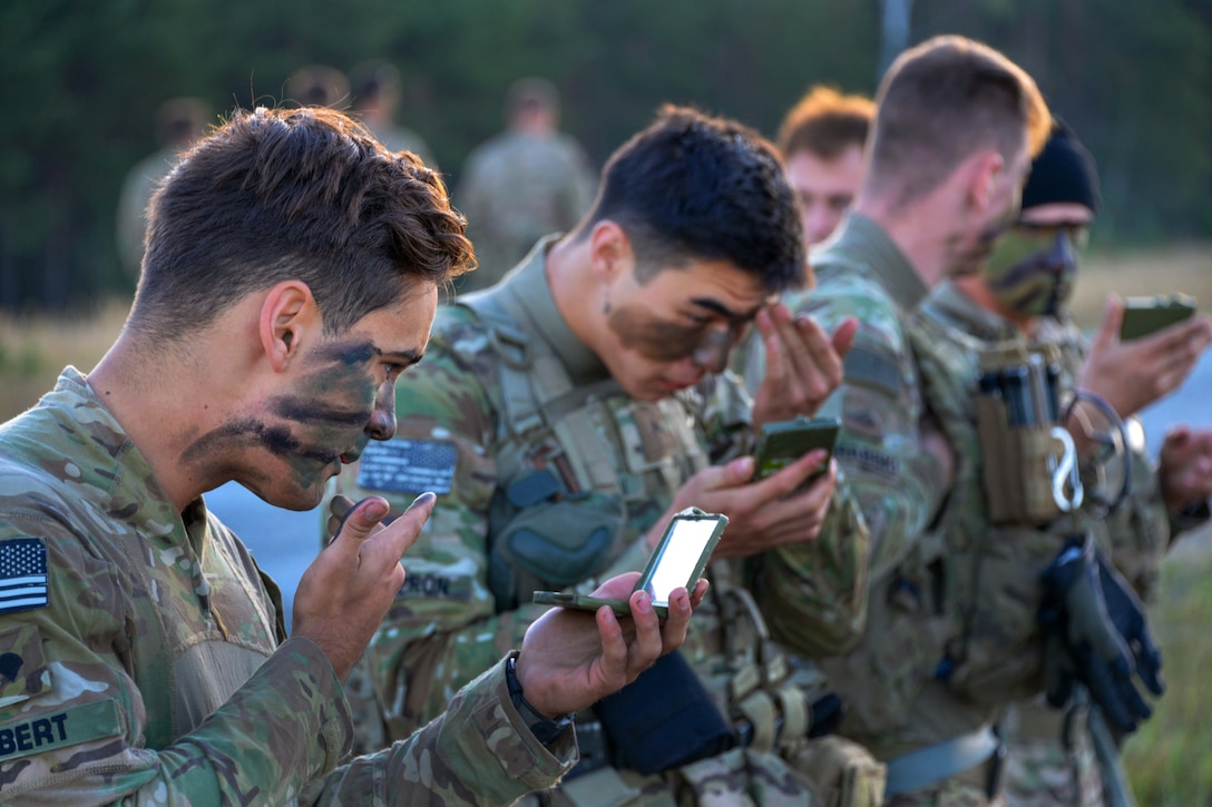 Soldiers apply camouflage face paint before conducting air assault training.