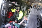 Flood victims hold hands aboard a UH-60 Black Hawk helicopter during an aerial evacuation over Marion County, South Carolina, Sept. 20, 2018. Pennsylvania Guard air crews joined to rescue them.