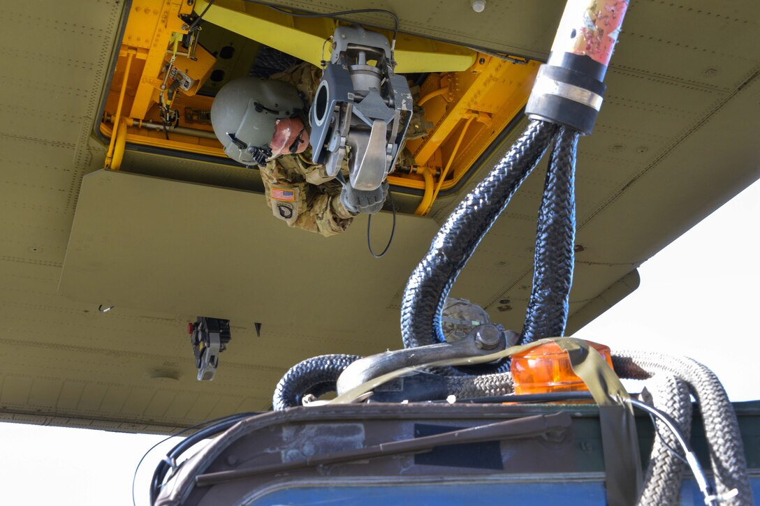 An Army crew chief prepares to sling-load a Humvee and trailer to a CH-47 Chinook helicopter.