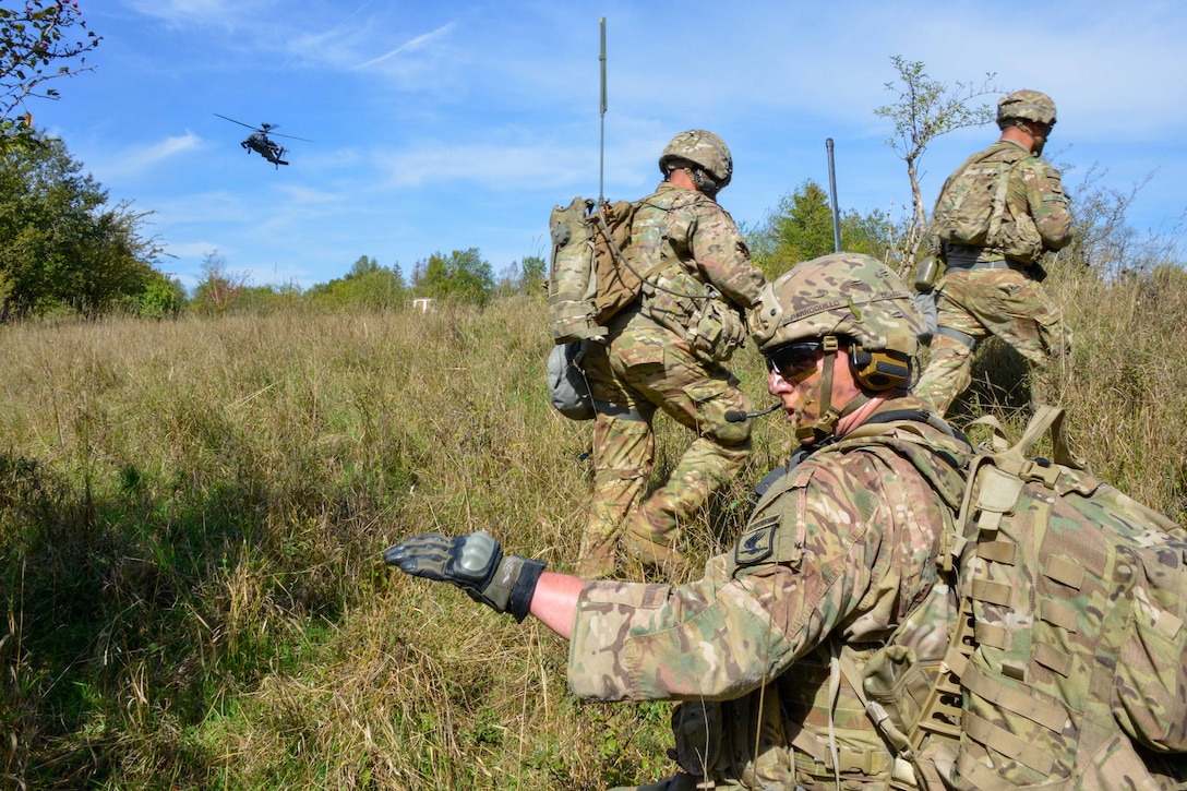 A soldier signals to members of his squad other soldiers during air assault training.