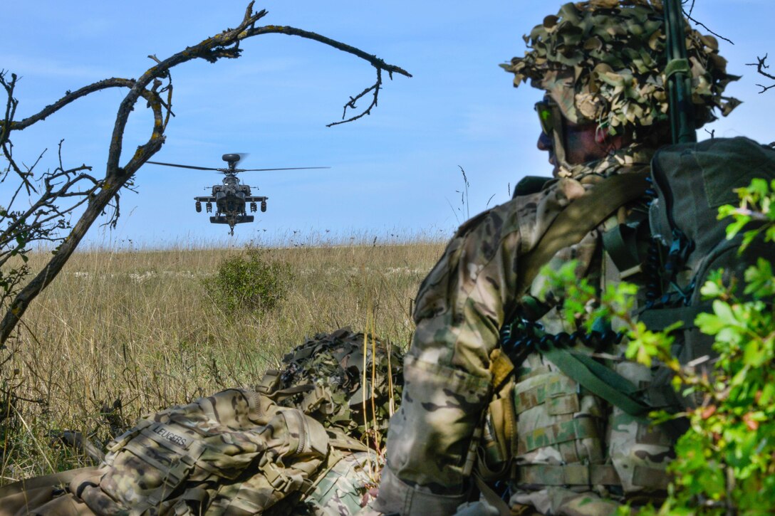 A helicopter hovers in front of soldiers, to provide aerial support coverage.