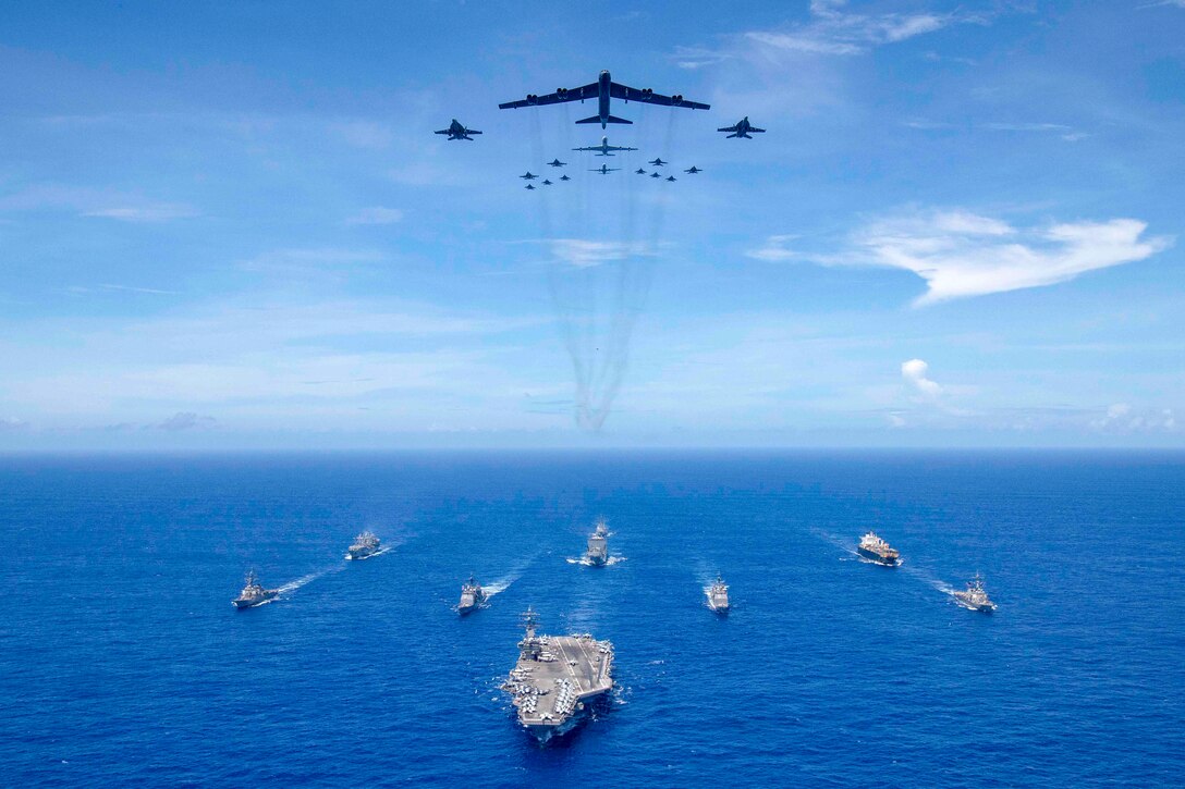 The aircraft carrier USS Ronald Reagan (CVN 76) leads a formation of Carrier Strike Group (CSG) 5 ships as Air Force B-52 Stratofortress aircraft and Navy F/A-18 Hornets pass overhead for a photo exercise during Valiant Shield 2018. The biennial, U.S.-only, field-training exercise focuses on integration of joint training among the Navy, Air Force and Marine Corps. (U.S. Navy photo by Mass Communication Specialist 3rd Class Erwin Miciano)
