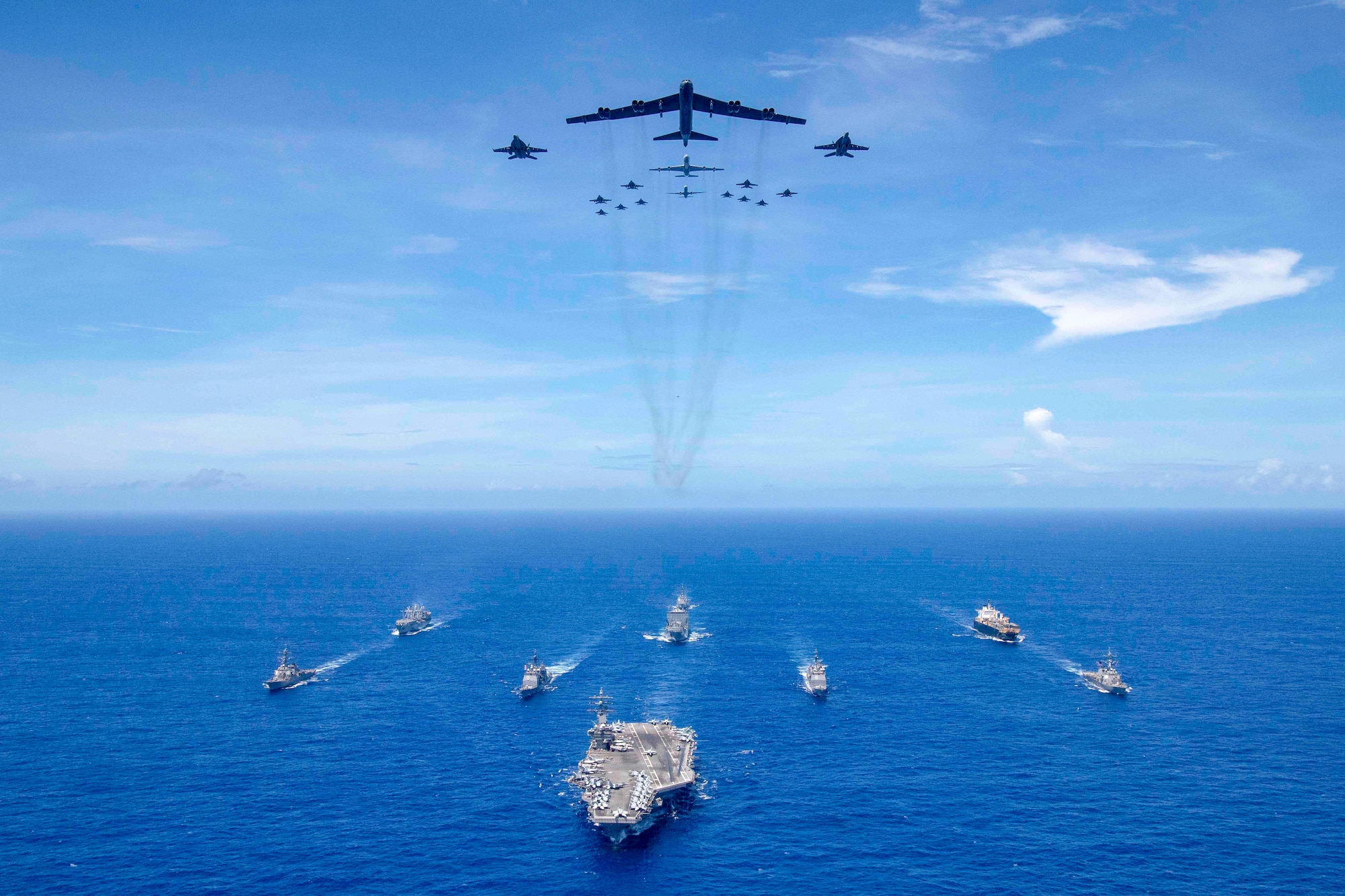 The aircraft carrier USS Ronald Reagan (CVN 76) leads a formation of Carrier Strike Group (CSG) 5 ships as Air Force B-52 Stratofortress aircraft and Navy F/A-18 Hornets pass overhead for a photo exercise during Valiant Shield 2018. The biennial, U.S.-only, field-training exercise focuses on integration of joint training among the Navy, Air Force and Marine Corps. (U.S. Navy photo by Mass Communication Specialist 3rd Class Erwin Miciano)