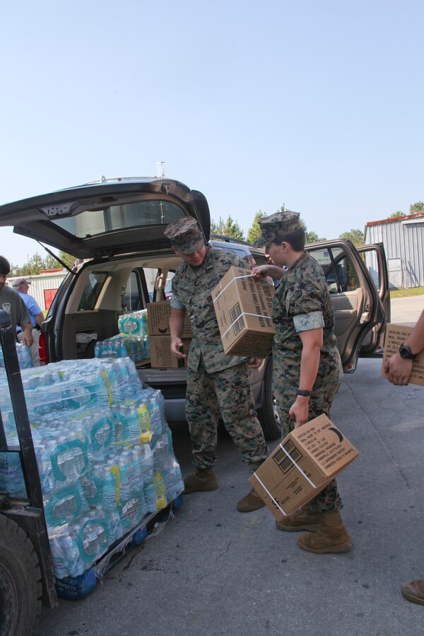 Lance Cpl.  James Negrete, left, and Lance Cpl. Britnee Johnson with Headquarters and Headquarters Squadron, Marine Corps Air Station Cherry Point, distribute food and water in a storm-ravaged neighborhood in New Bern, N.C., Sept. 20, 2018. U.S. Marines, and Soldiers with the U.S. Army National Guard, came together to support local communities trying to recover from Hurricane Florence. Negrete is a postal clerk and Johnson is a legal clerk with H&HS. (U.S. Marine Corps photo by: Lance Cpl. Alexandra Santos Arambulo)