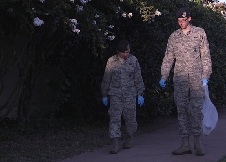 U.S. Air Force Airmen 1st Class Tyler Coulter and Miguel Barajas, both assigned to the 97th Security Forces Squadron, walk down a sidewalk scanning for trash, Sep. 20, 2018, at Altus Air Force Base, Okla. Airmen perform base clean-ups every third Thursday of the month, during which Airmen walk around the entire base and pick up garbage. (U.S. Air Force photo by Airman 1st Class Dylan Murakami)