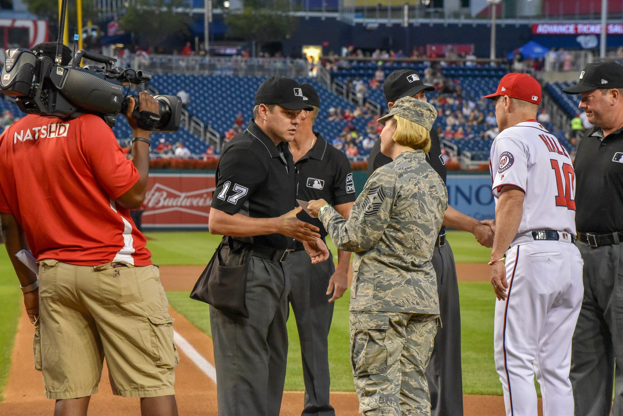 An Airman gives a card to a baseball official.