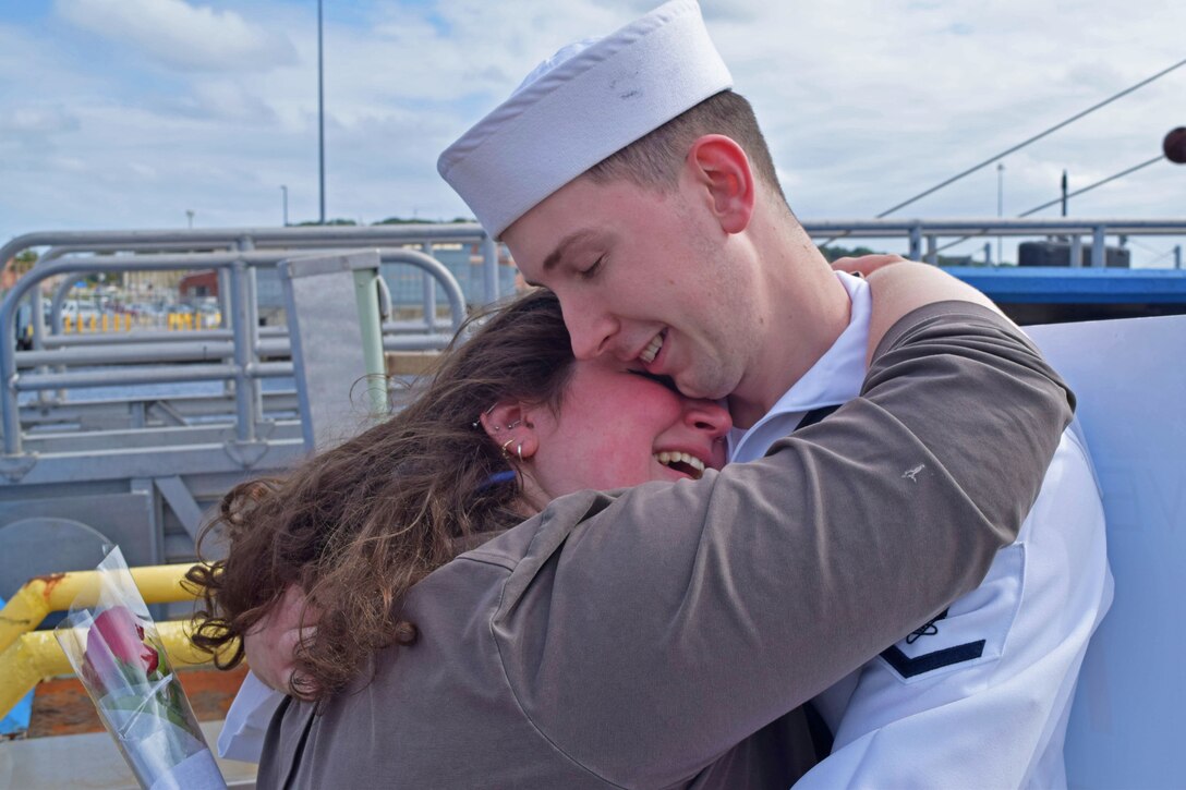 A sailor hugs a loved one.